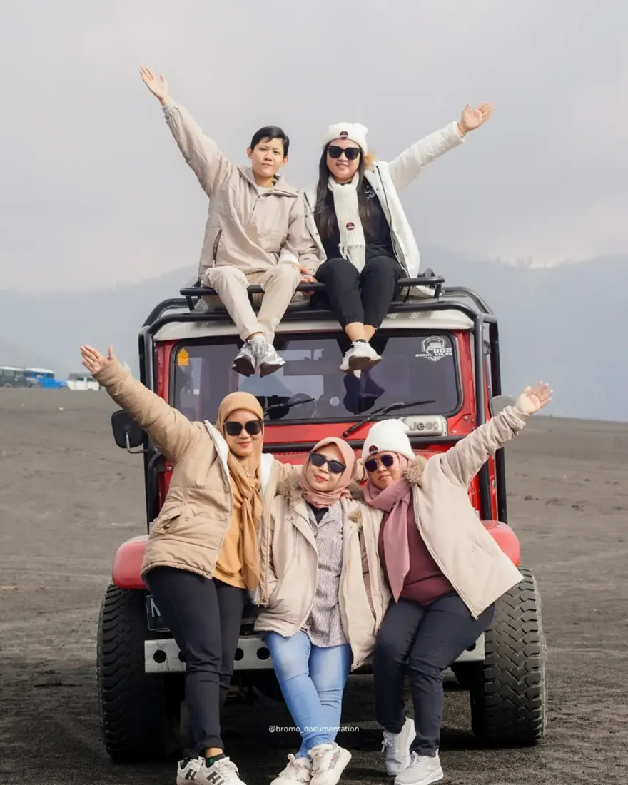 Rombongan tamu berpose di atas jeep merah